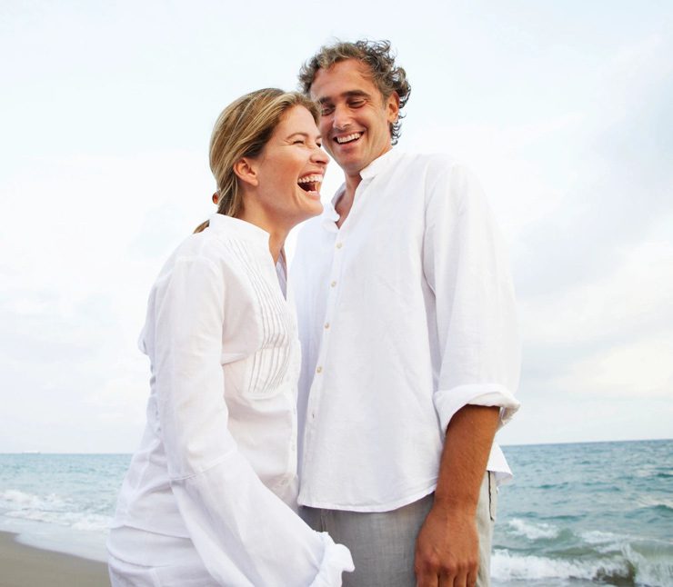 A man and woman standing next to each other on the beach.