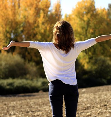 A woman standing in the middle of an open field.